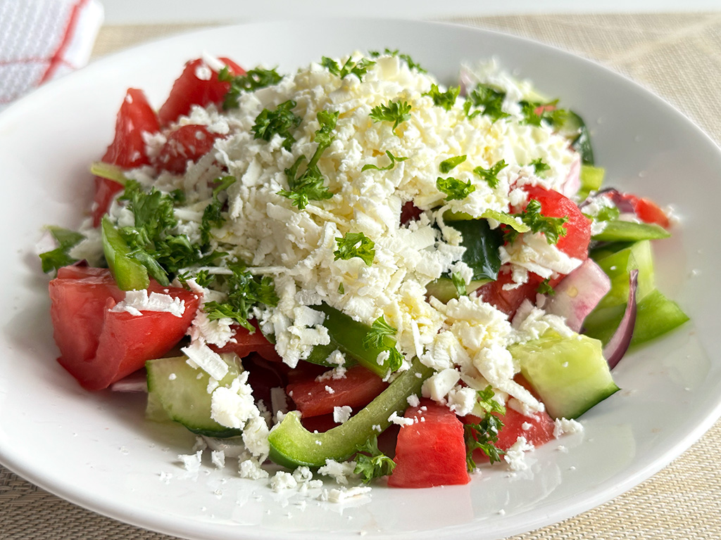 Shopska salad in a bowl on a placemat