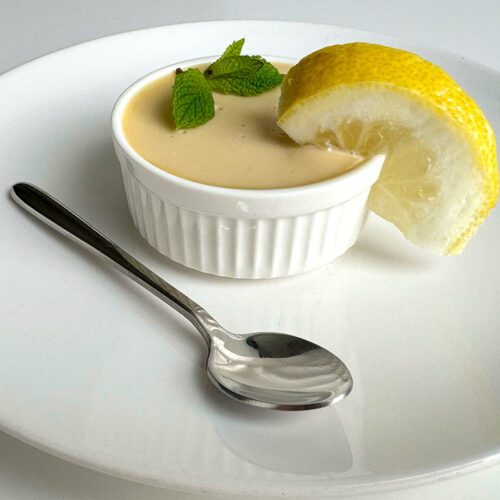 Posset in a ramekin garnished with mint and lemon