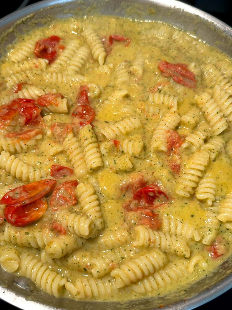 Pasta in a pan with sauce from zucchini and cherry tomatoes